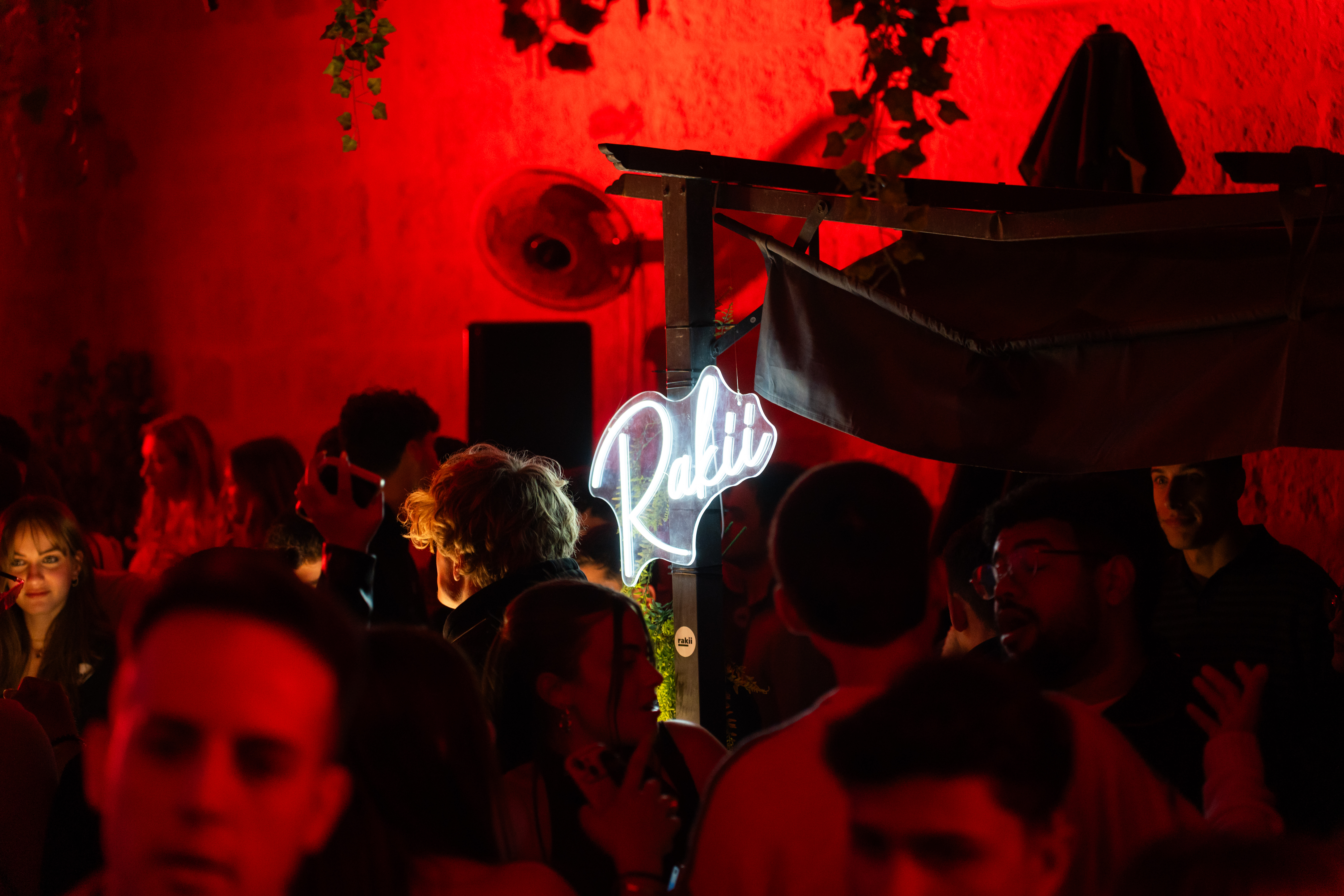 Rakii neon sign glowing above the crowd